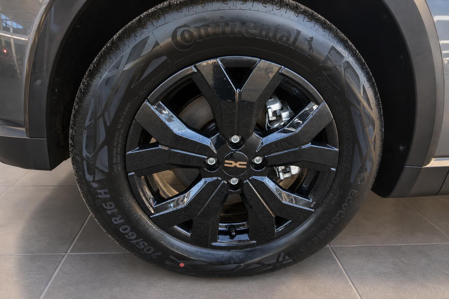 Schwarze Leichtmetallfelge mit Continental-Reifen und SsangYong-Logo an grauem Fahrzeug