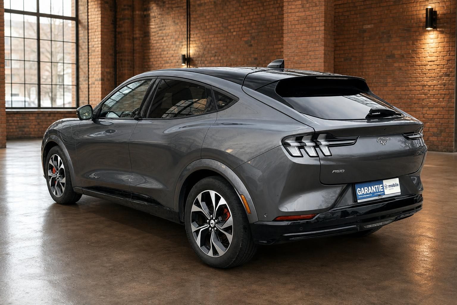 Ford Mustang Mach-E in Grau, Heckansicht in Industrie-Ambiente