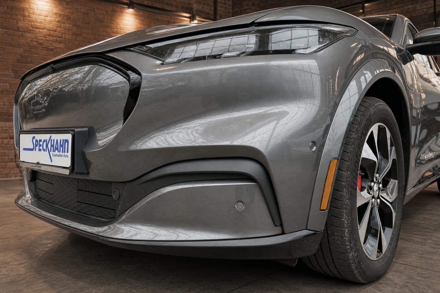 Ford Mustang Mach-E grau, Frontstoßstange und Felge Detailansicht