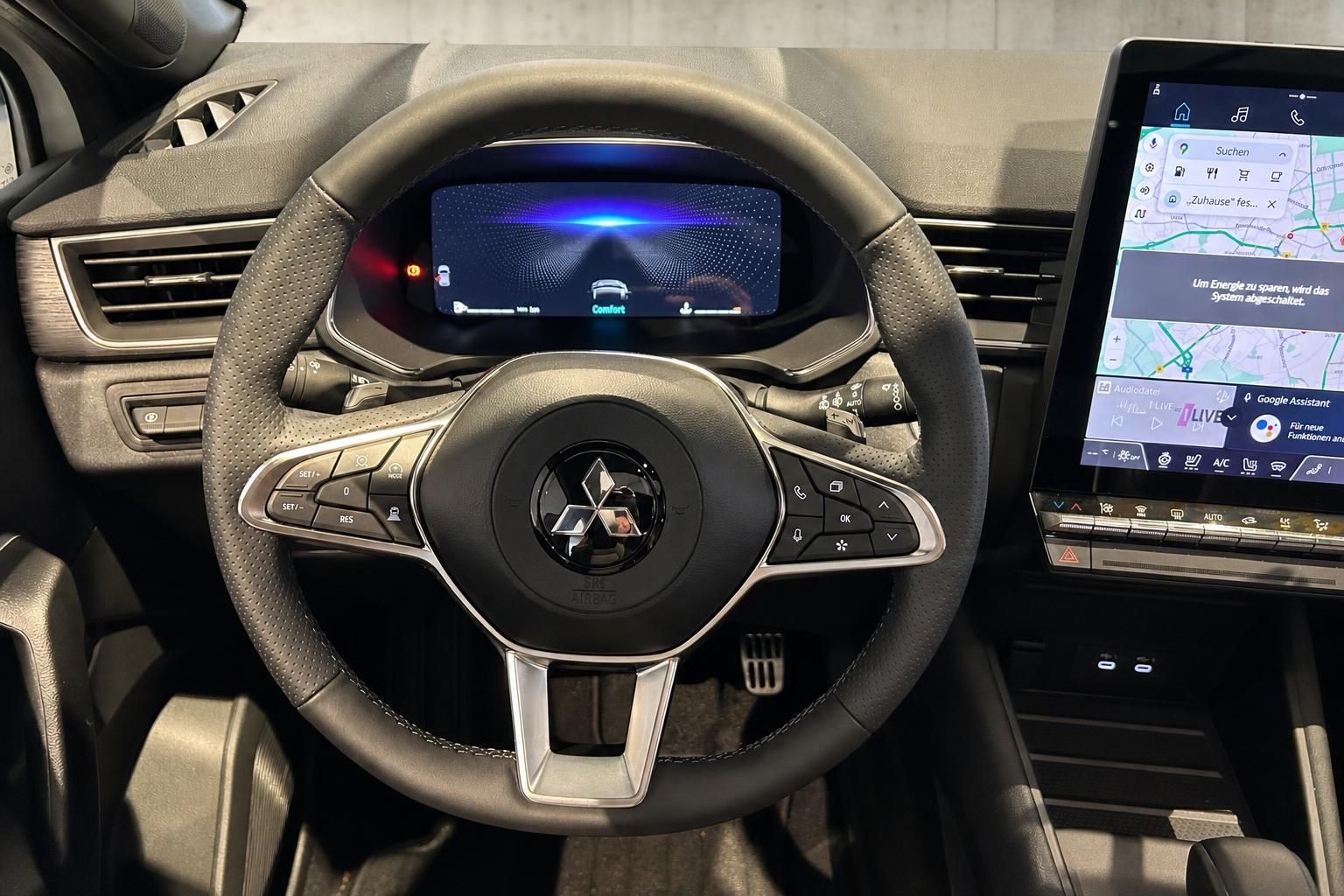 Lenkrad mit Mitsubishi Logo und digitalem Kombiinstrument im Cockpit