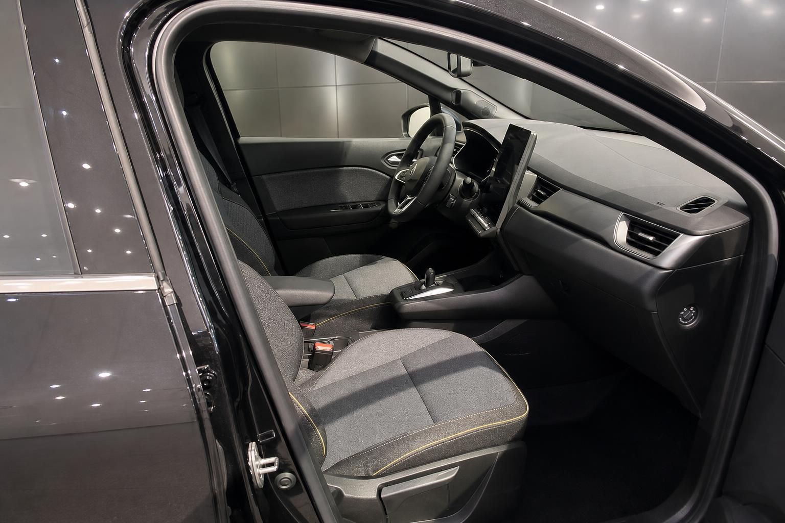 Renault Innenraum Fahrerseite – schwarze Sitze mit gelber Ziernaht, Lenkrad und Touchscreen