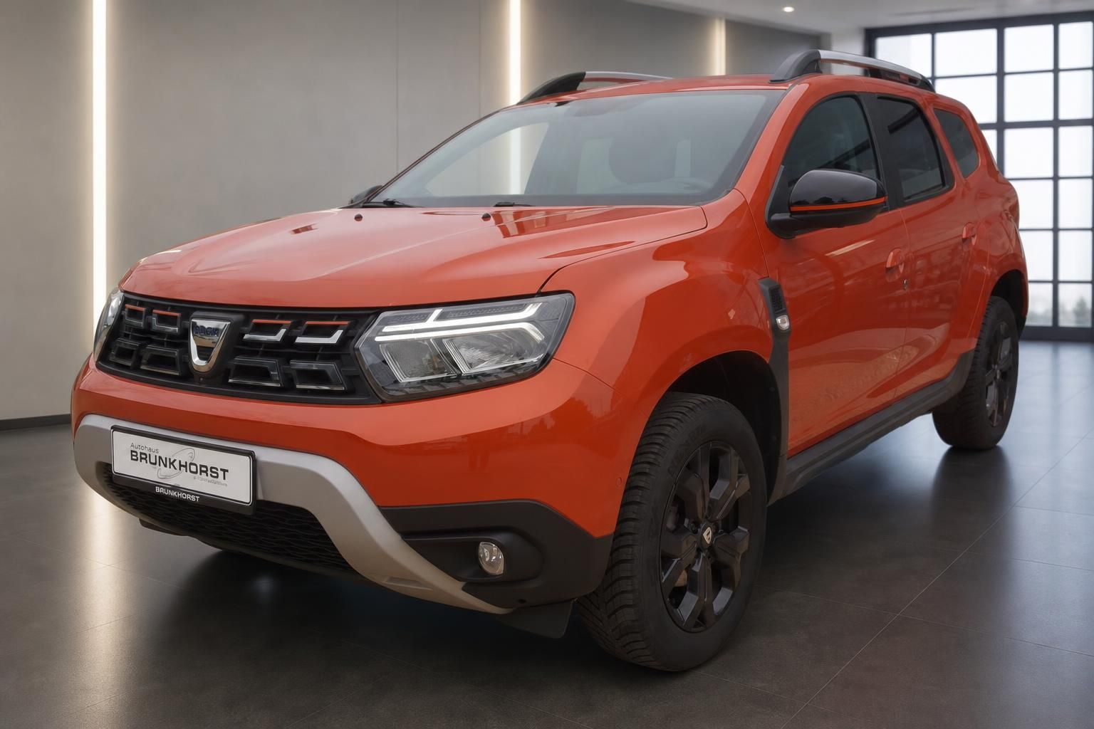 Dacia Duster orange Seitenansicht im Autohaus mit modernen Felgen