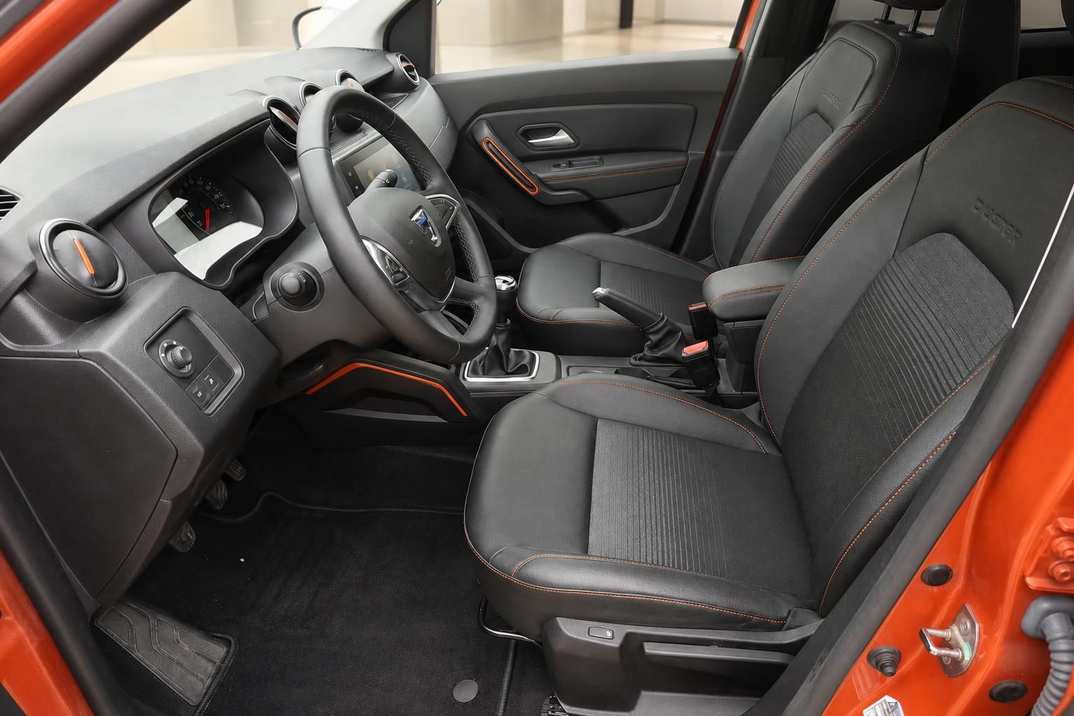 Dacia Duster Innenraum mit schwarzen Sitzen, Lenkrad und orangenen Akzenten