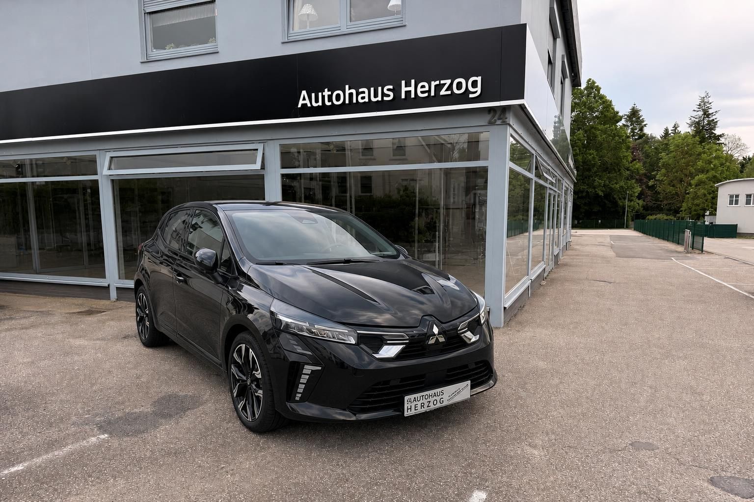 Schwarzer Mitsubishi vor Autohaus Herzog - moderne Kompaktlimousine mit LED-Scheinwerfern und Sportfelgen
