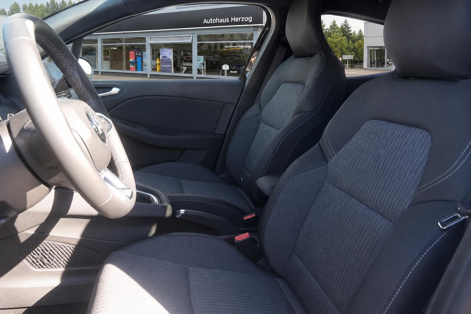 Mitsubishi Fahrzeuginnenraum mit dunklen Stoffsitzen und seitlicher Ansicht durch geöffnete Fahrertür