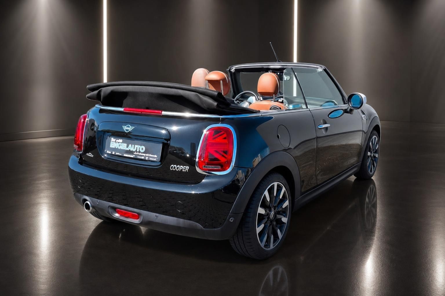 MINI Cooper Cabrio in Midnight Black - Heckansicht mit geöffnetem Verdeck und orangem Interieur