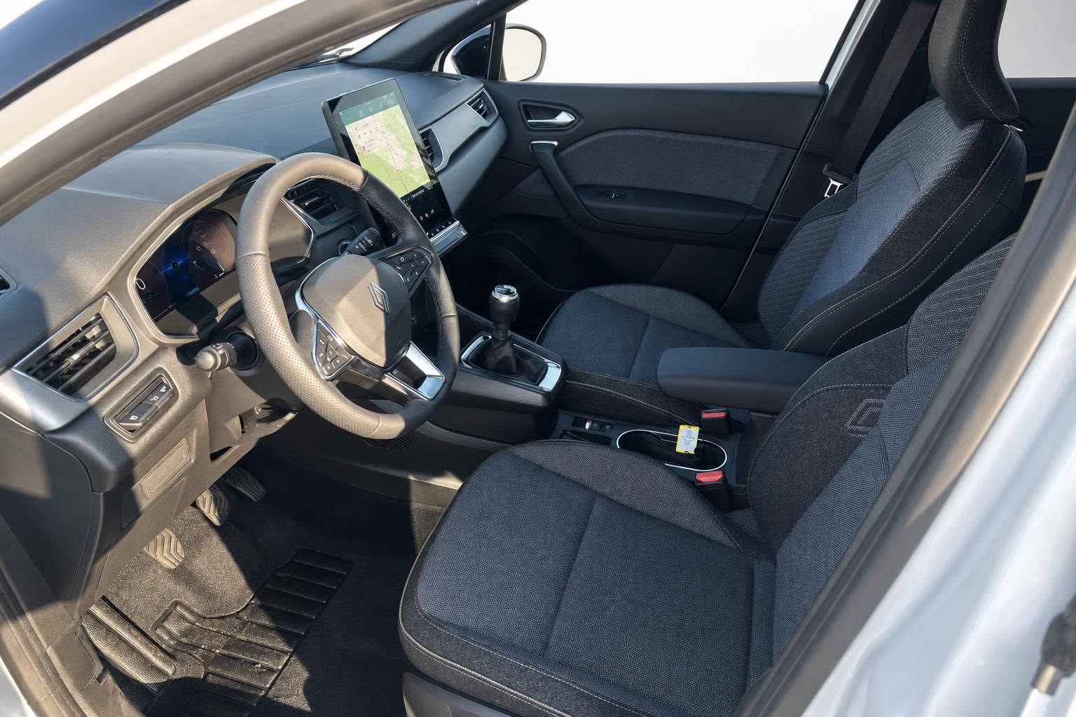 Renault Captur Innenraum mit schwarzen Sitzen, Lenkrad und Navigationssystem seitliche Ansicht
