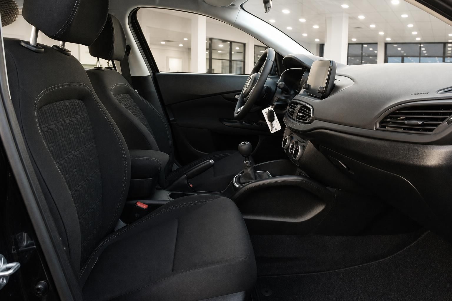 Fiat Tipo Innenraum – Vordersitze mit schwarzem Stoffbezug, Mittelkonsole und Lenkrad
