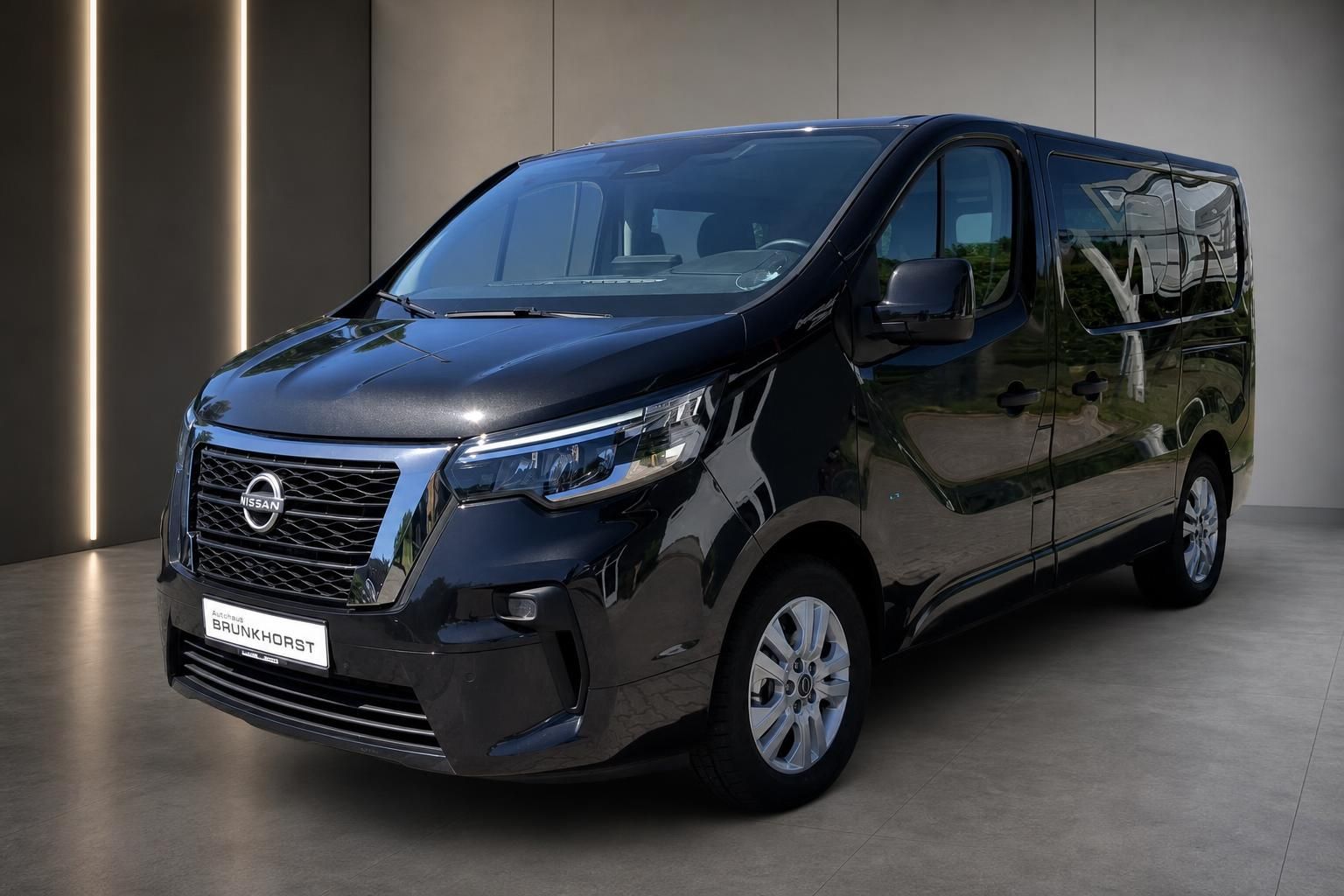 Nissan Primastar Transporter schwarz Seitenansicht mit Alufelgen im modernen Autohaus-Showroom
