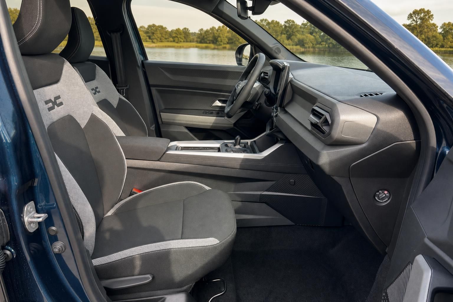 Fahrzeug-Innenraum mit Fahrer- und Beifahrersitzen, Mittelkonsole und Blick durch offene Türe