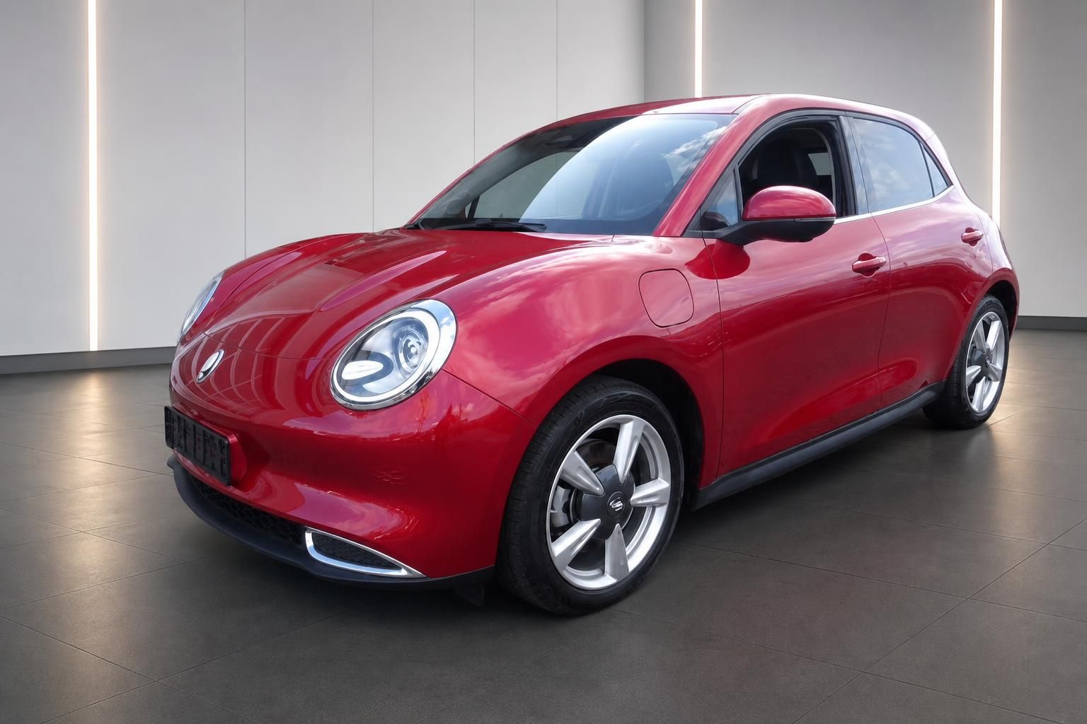 Roter Elektro-Kleinwagen Frontansicht schräg – moderne Scheinwerfer und Alufelgen im Showroom