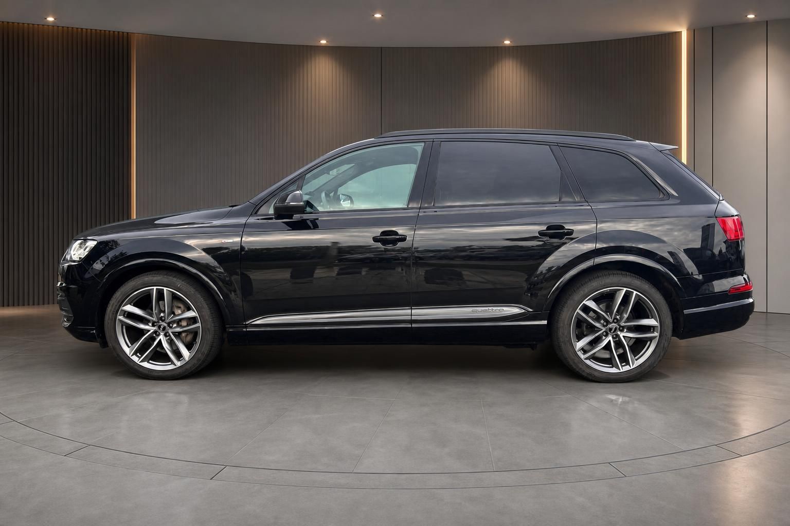 Audi Q7 quattro schwarz Seitenansicht mit 21-Zoll-Alufelgen im Showroom