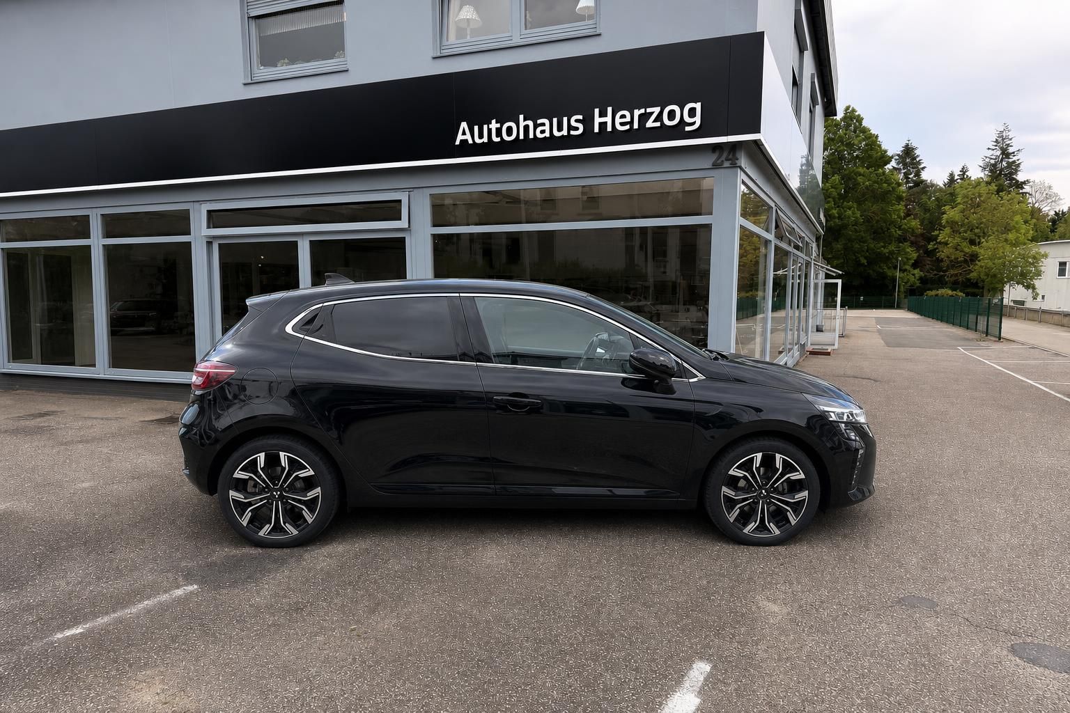 Schwarzer Mitsubishi Seitenansicht vor Autohaus - kompakter SUV mit kontrastierenden Felgen und Seitenlinie