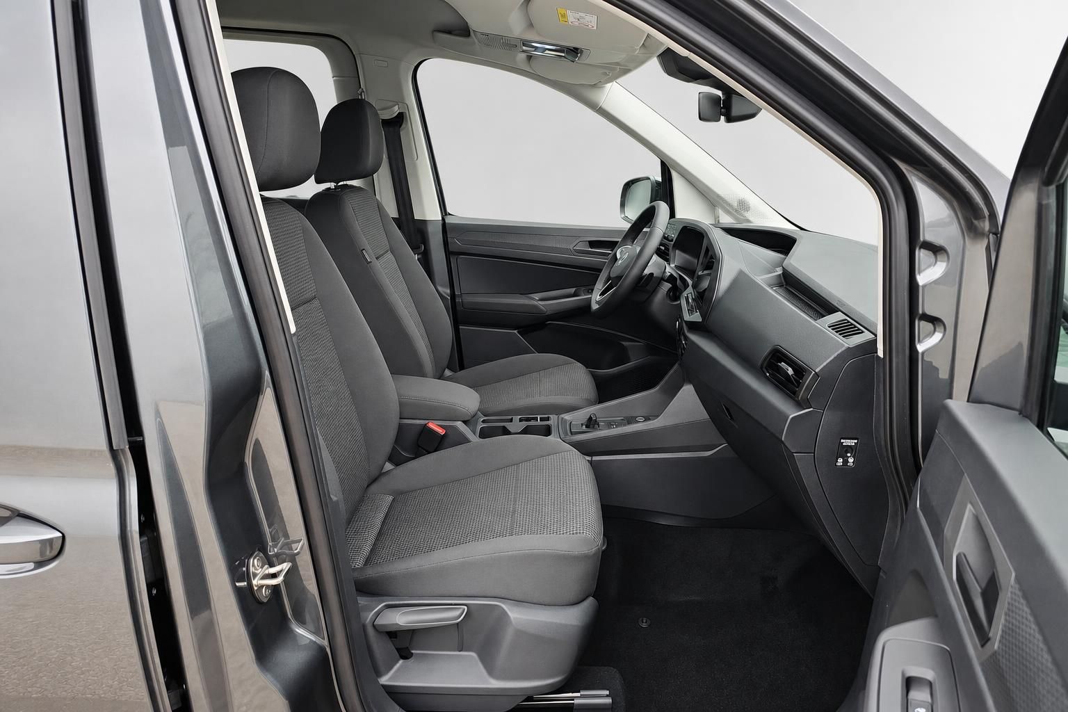 VW Caddy Innenraum mit Vordersitzen und Armaturenbrett, Blick durch offene Tür