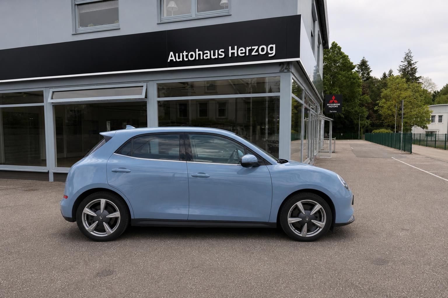 GWM ORA hellblaues Elektrofahrzeug Seitenansicht vor Autohaus Herzog - modernes E-Auto mit sportlichen Felgen