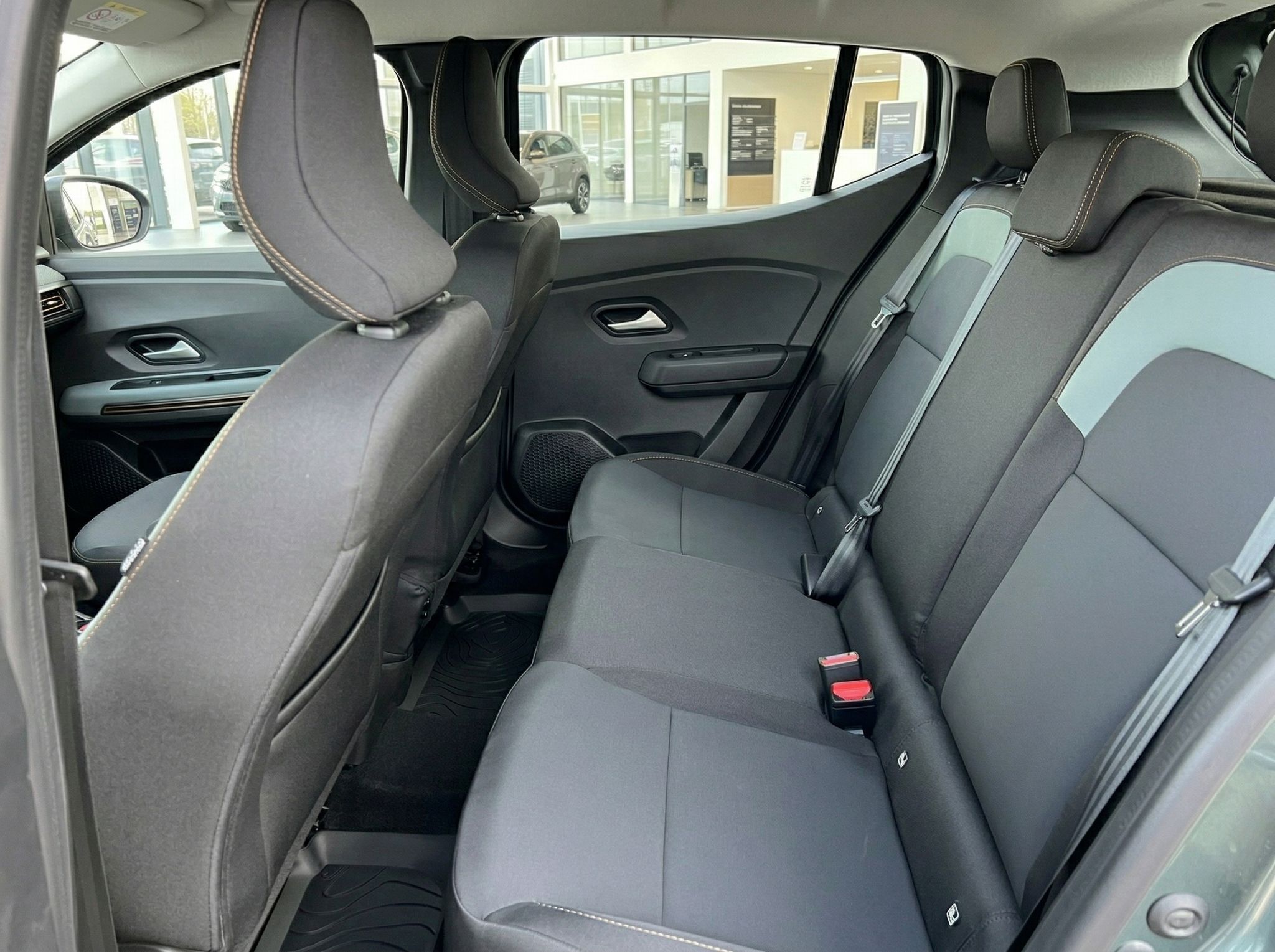 Rücksitzbank eines Fahrzeugs mit grauen Stoffsitzen und Sicherheitsgurten