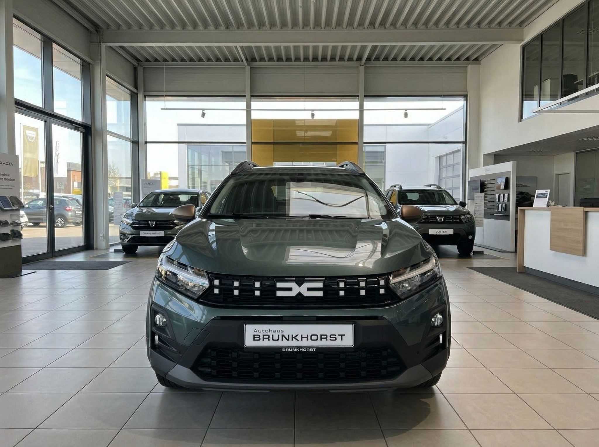 Dacia Fahrzeug Frontansicht in grün-metallic im modernen Autohaus Showroom