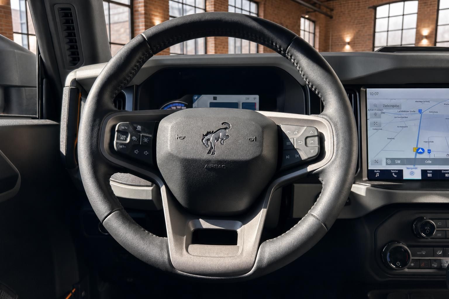 Ford Bronco Lenkrad mit Bronco-Logo und Navigationsdisplay im Hintergrund
