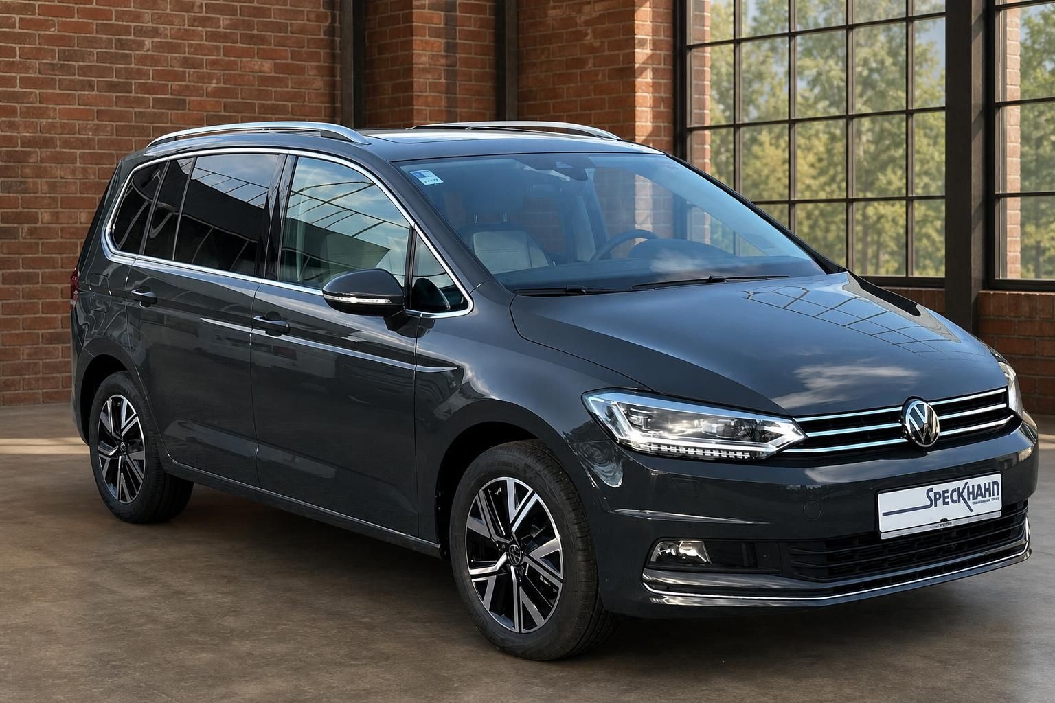 VW Touran dunkelgrau Frontansicht seitlich vor Glasfassade