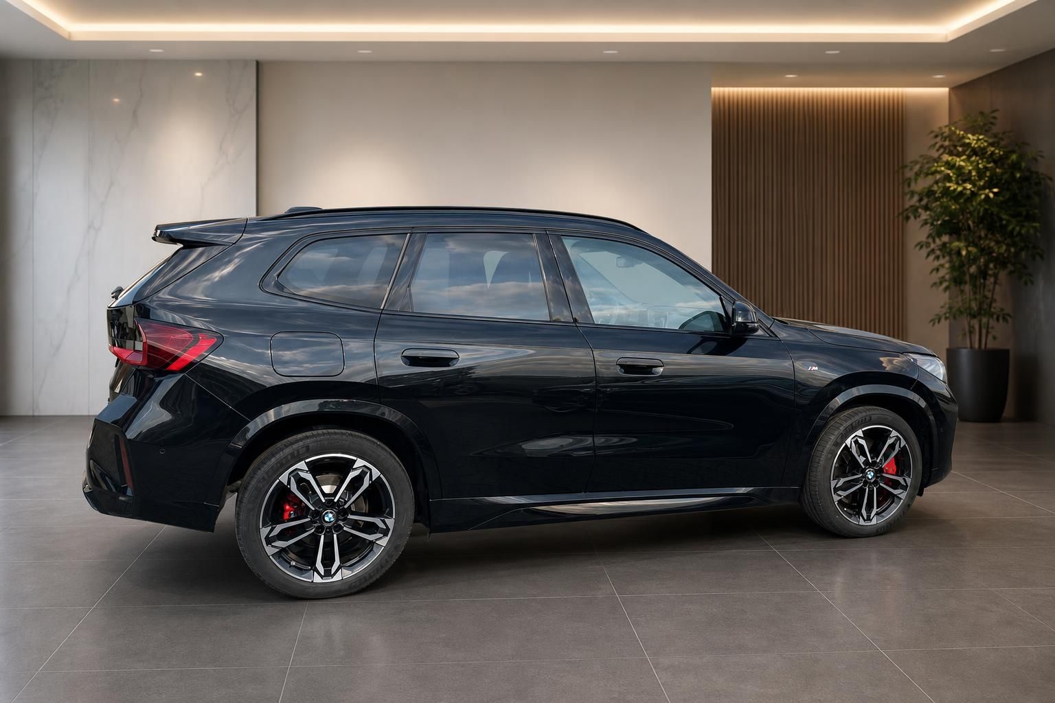 BMW X1 schwarz Seitenansicht mit roten Bremssaetteln im Showroom