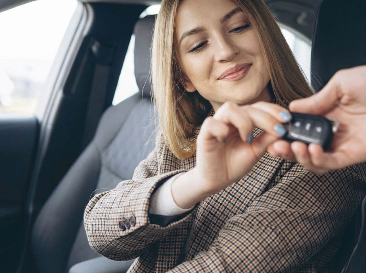 Frau erhält Autoschlüssel im Fahrzeuginnenraum – Fahrzeugübergabe im Auto