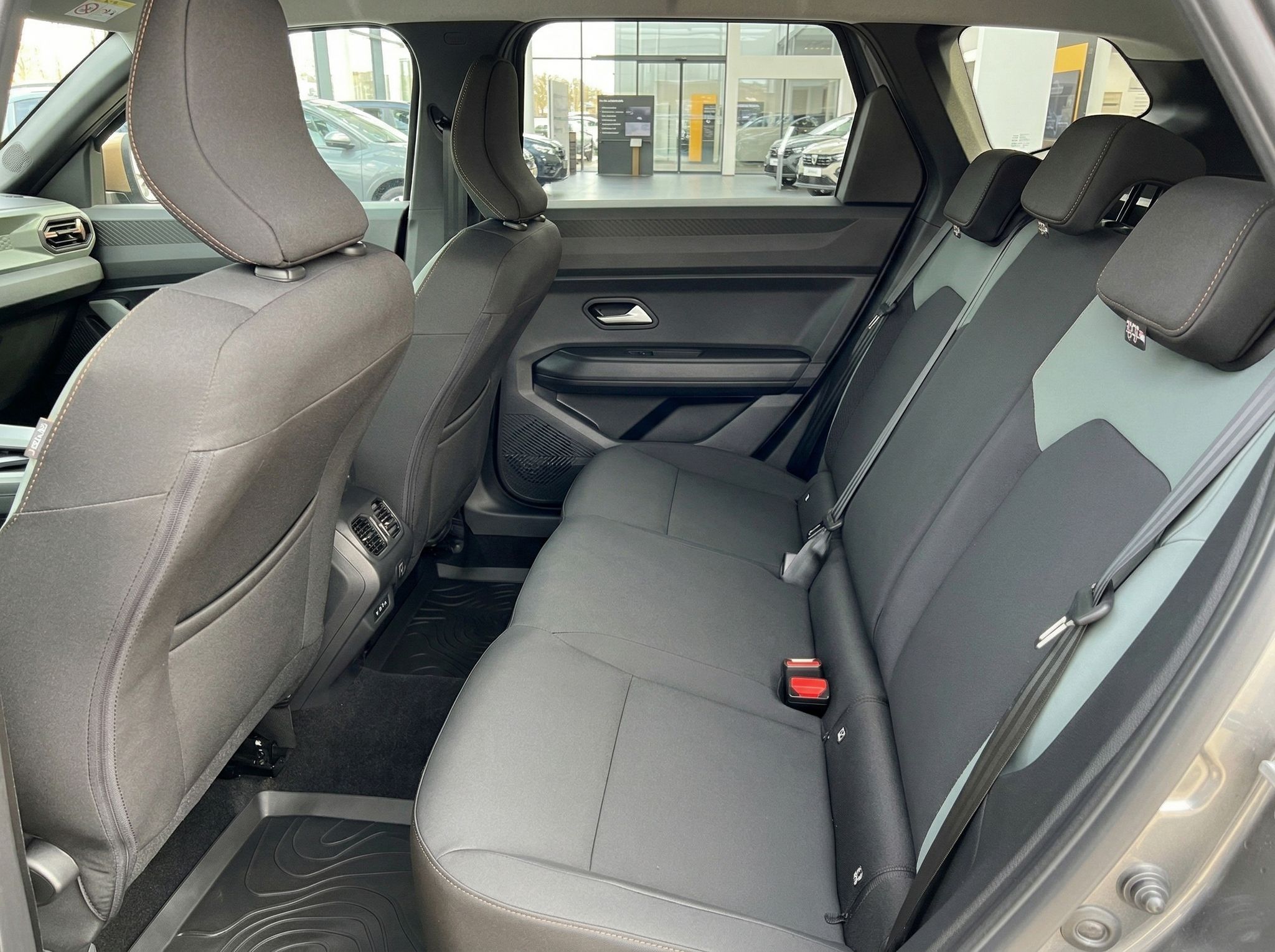 Rücksitzbank eines Fahrzeugs mit grauen Polstern und Sicherheitsgurten