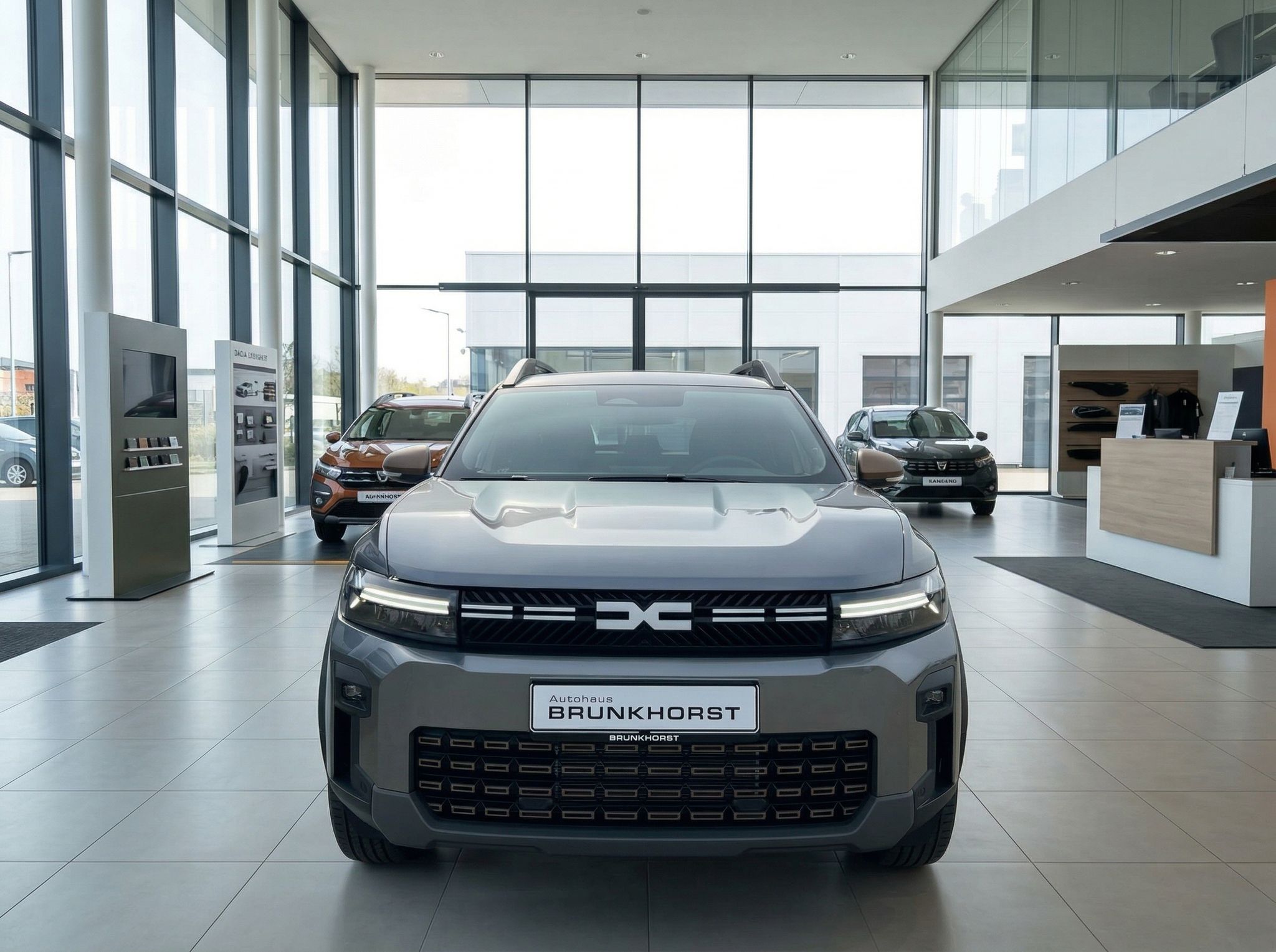 Grauer Dacia SUV Frontansicht im Autohaus Showroom mit großen Fenstern und modernem Interieur