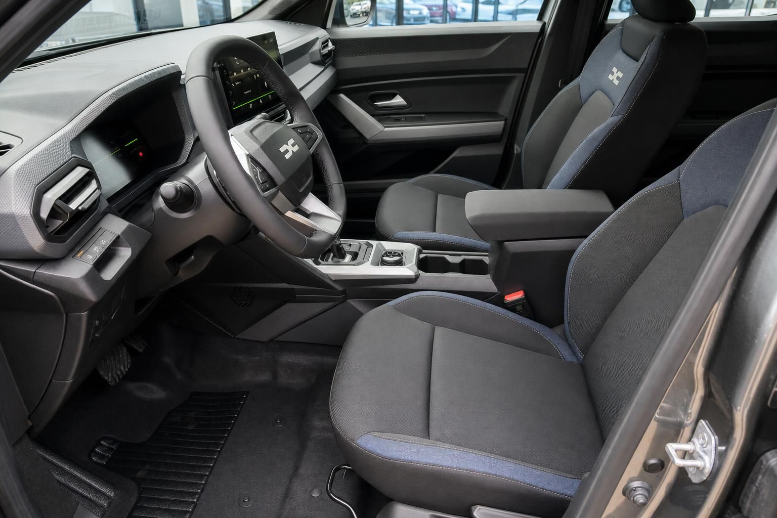 Moderner Fahrzeuginnenraum mit grau-blauen Sitzen, Lenkrad und digitalem Cockpit