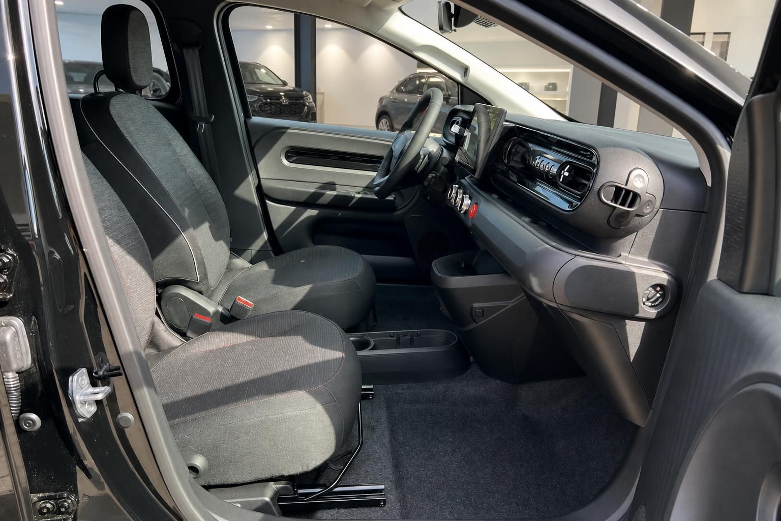 Fahrzeuginnenraum mit grauen Stoffsitzen und modernem Armaturenbrett - Beifahrerseite geöffnet