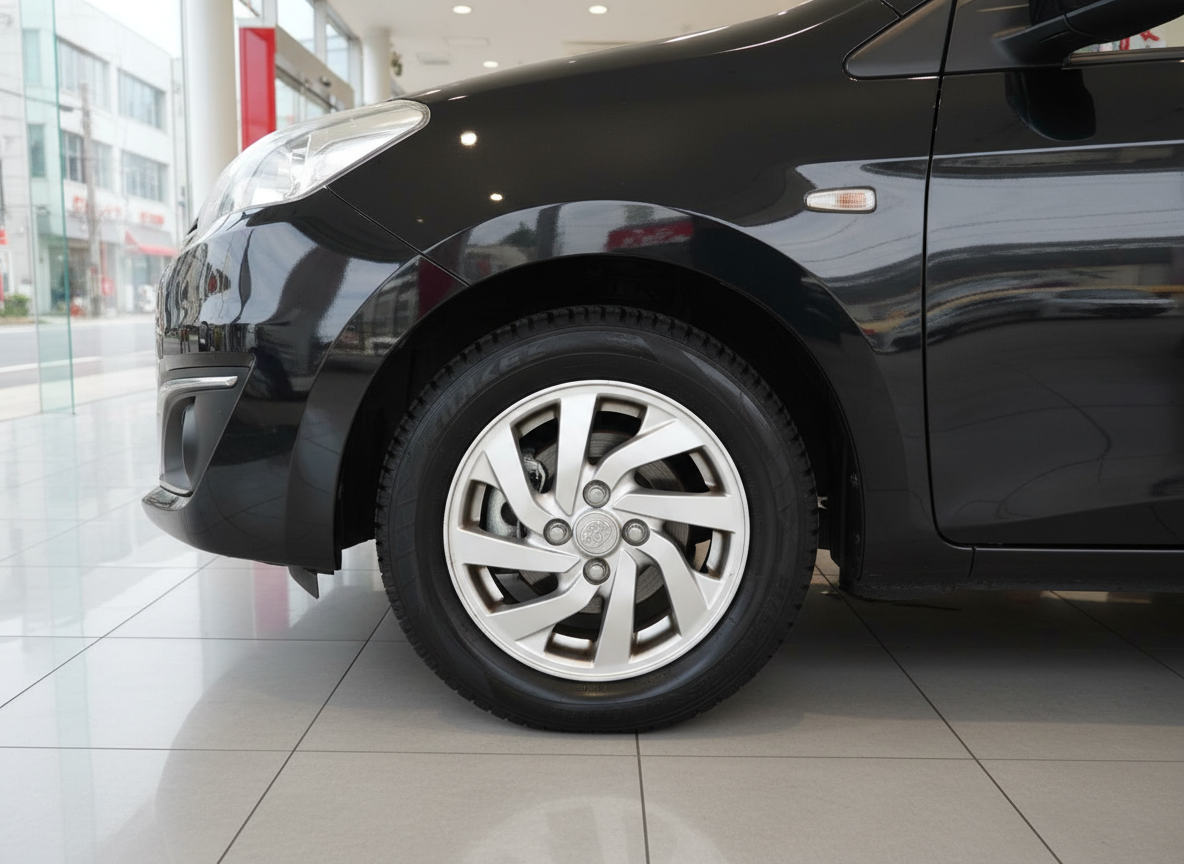 Schwarzer Pkw Detailaufnahme Vorderrad mit Silber-Felge im Autohaus-Showroom