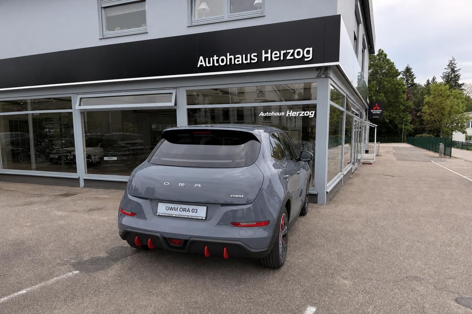 GWM Ora 03 Heckansicht mit rotem Diffusor vor Autohaus Herzog