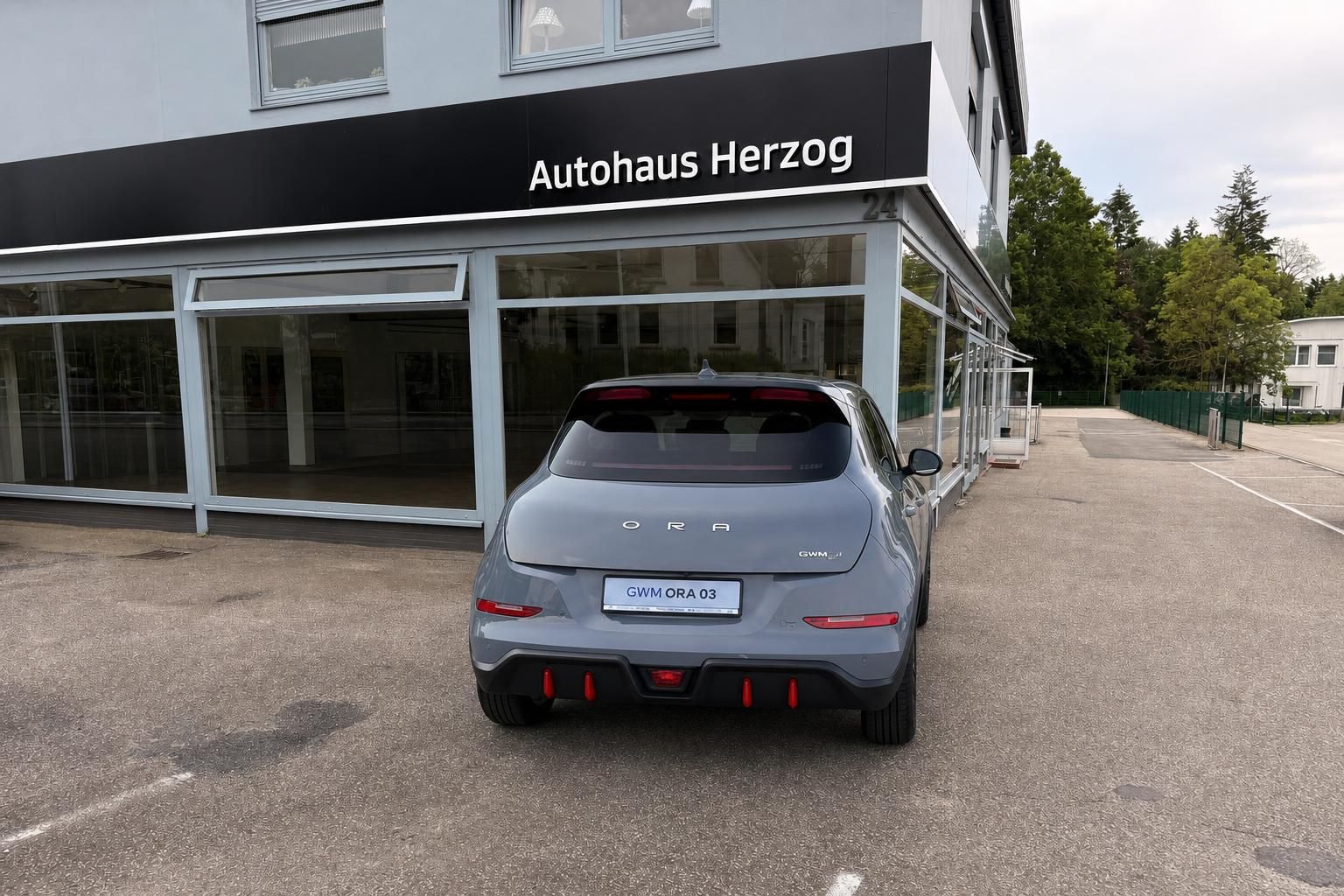 GWM Ora 03 in Grau, Heckansicht vor Autohaus Herzog