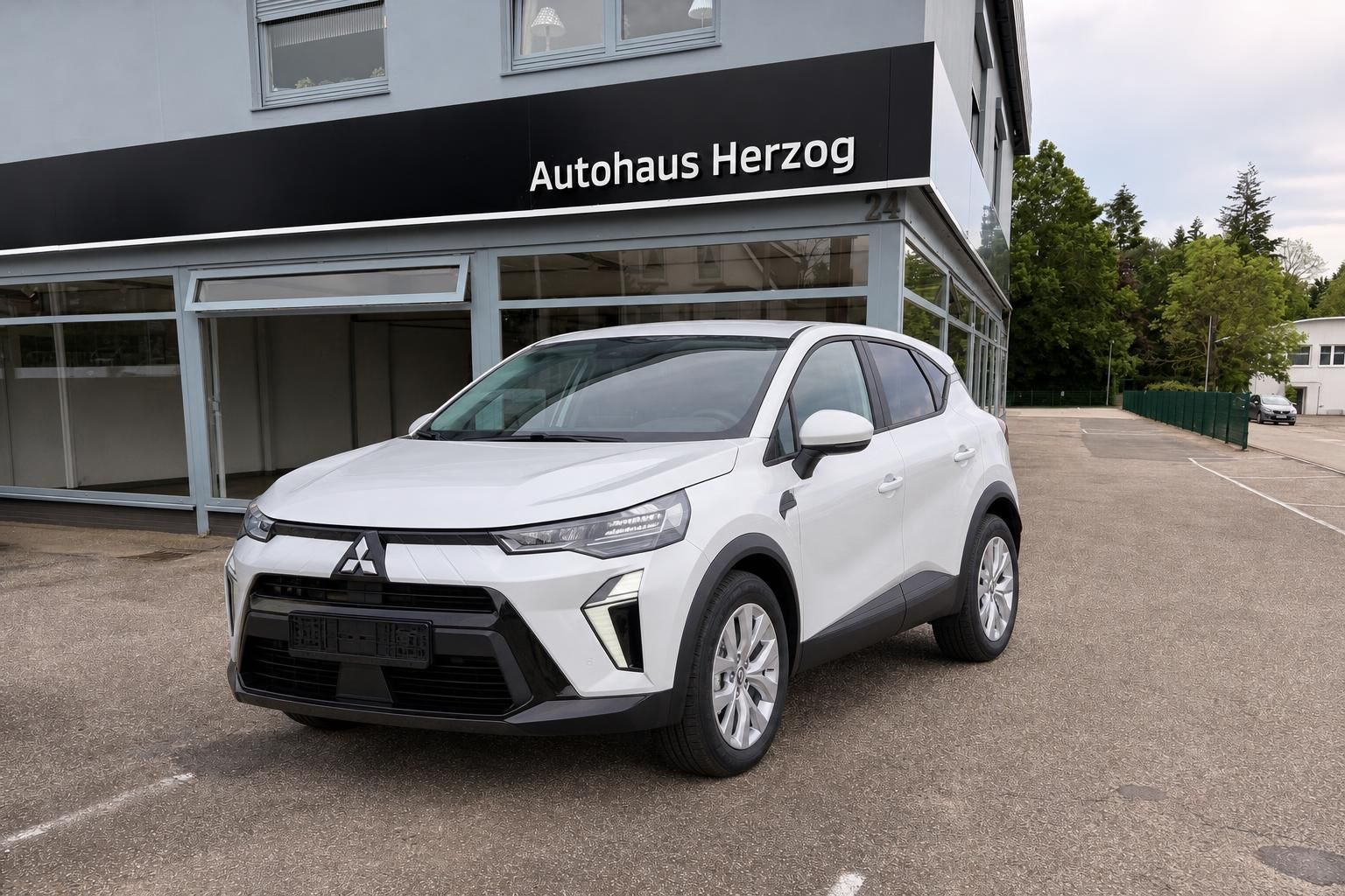 Mitsubishi SUV weiß Frontansicht vor Autohaus Herzog Gebäude mit Schaufenster