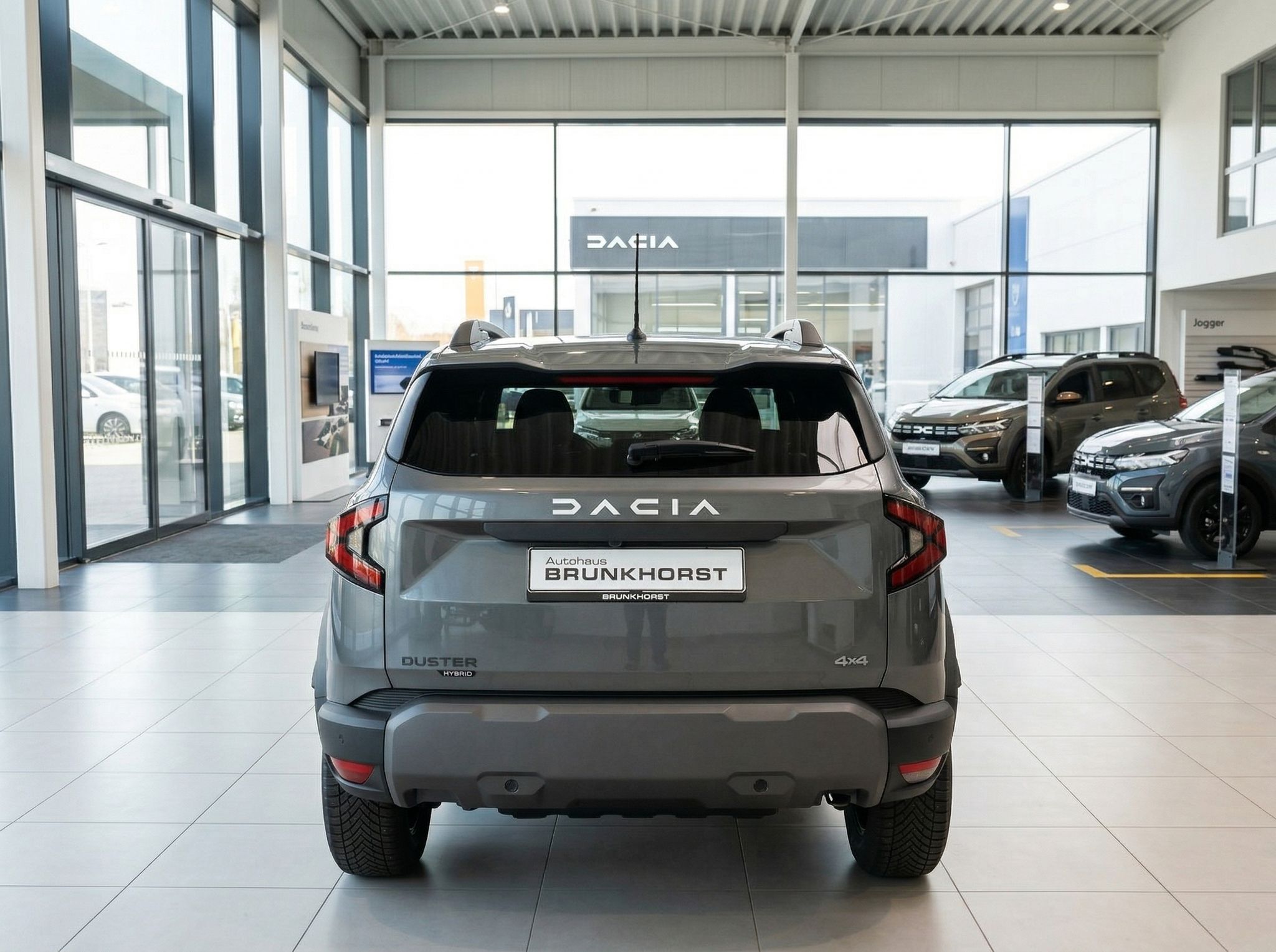 Dacia Duster Hybrid 4x4 grau - Heckansicht im Autohaus mit DACIA Schriftzug