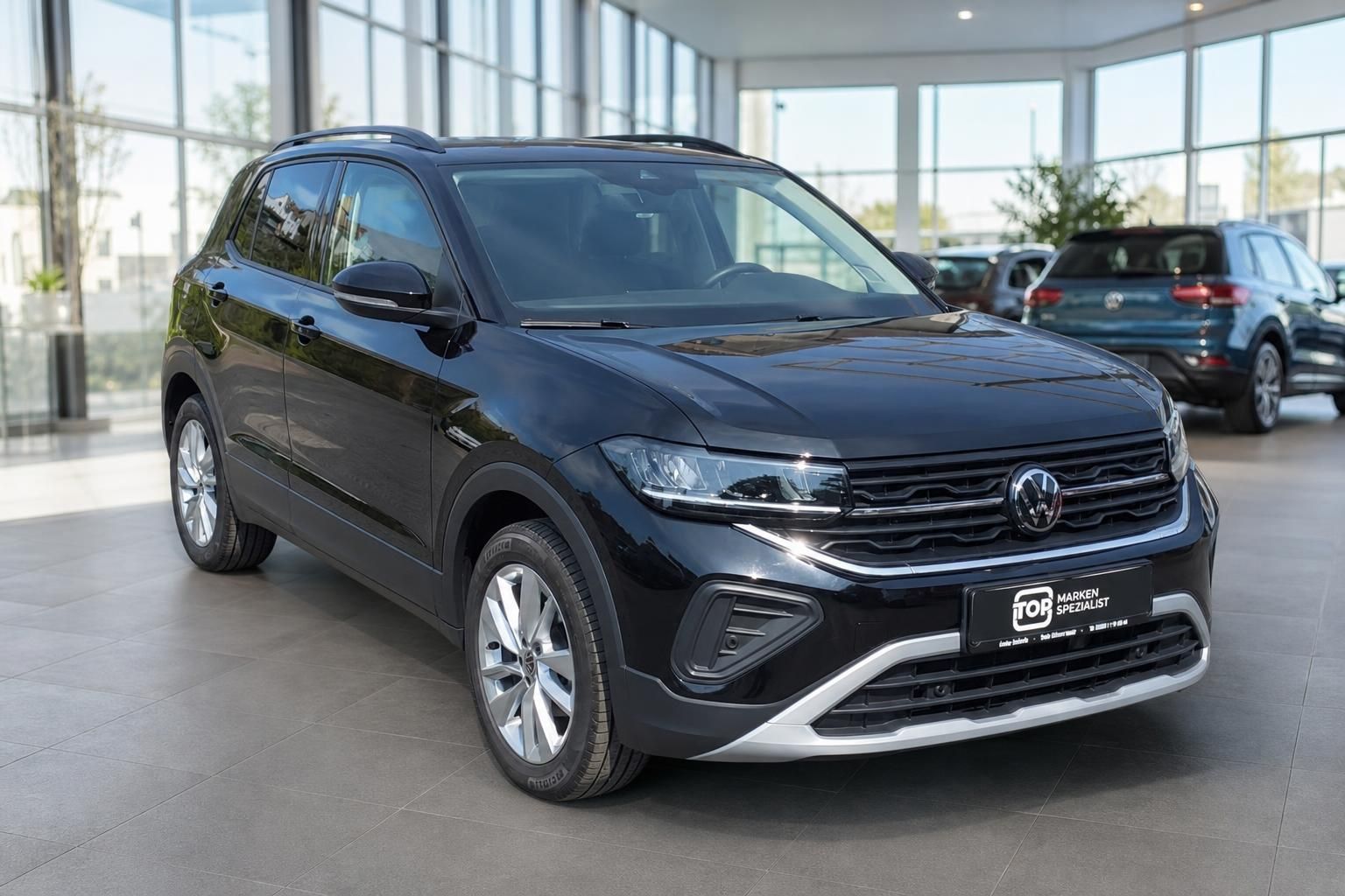 Schwarzer VW Crossover SUV Schrägansicht vorne links im hellen Autohaus-Showroom mit Glasfassade