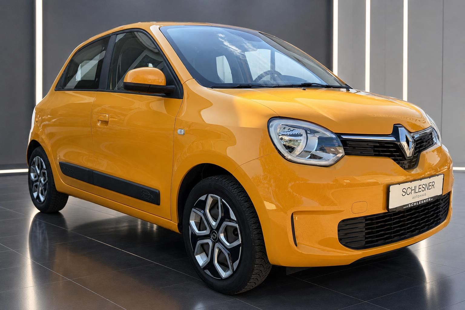 Renault Twingo in Gelb, Frontansicht seitlich glaenzend im Showroom