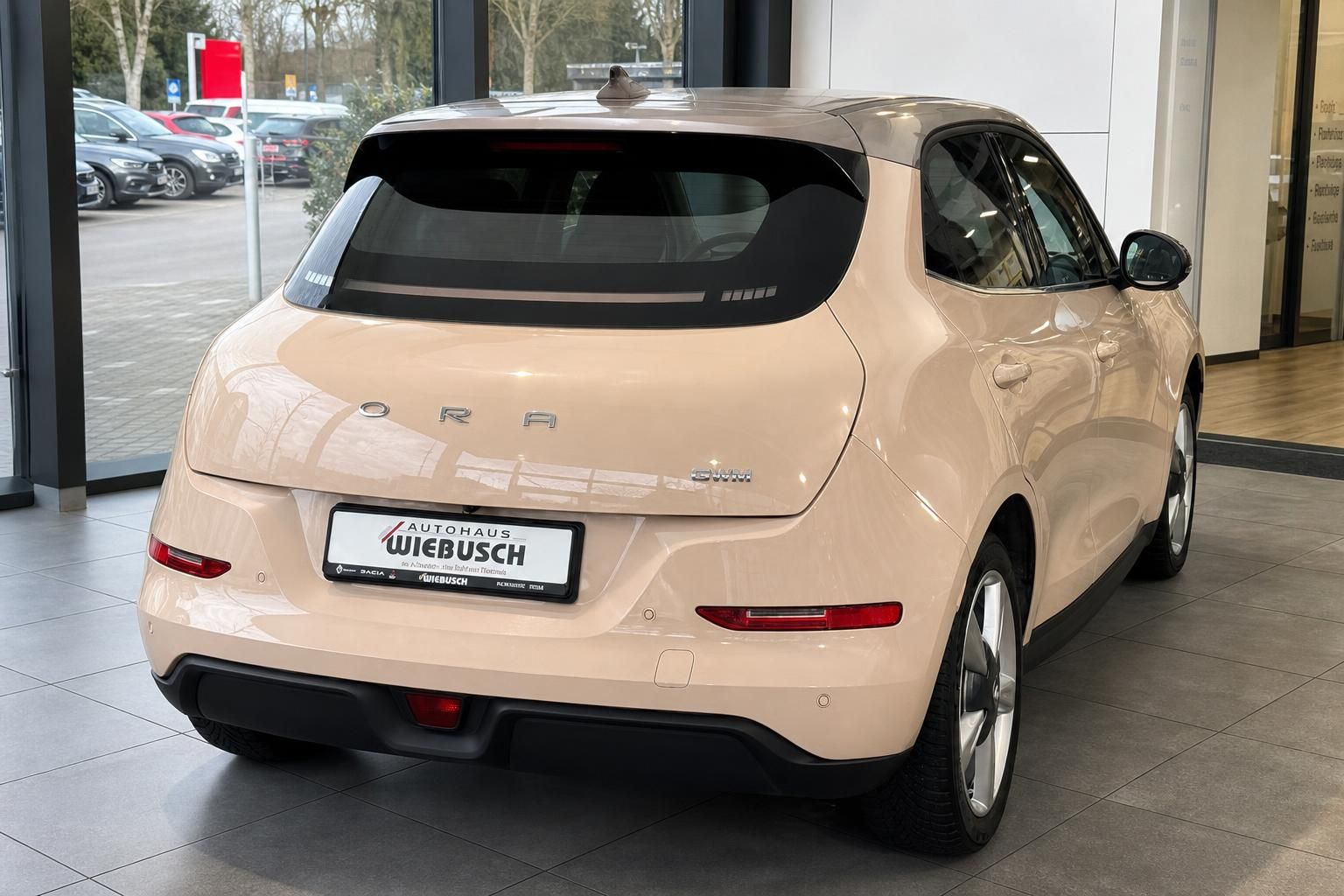 Heckansicht eines beigen Elektrofahrzeugs mit Autohaus Wiebusch Kennzeichen im Showroom