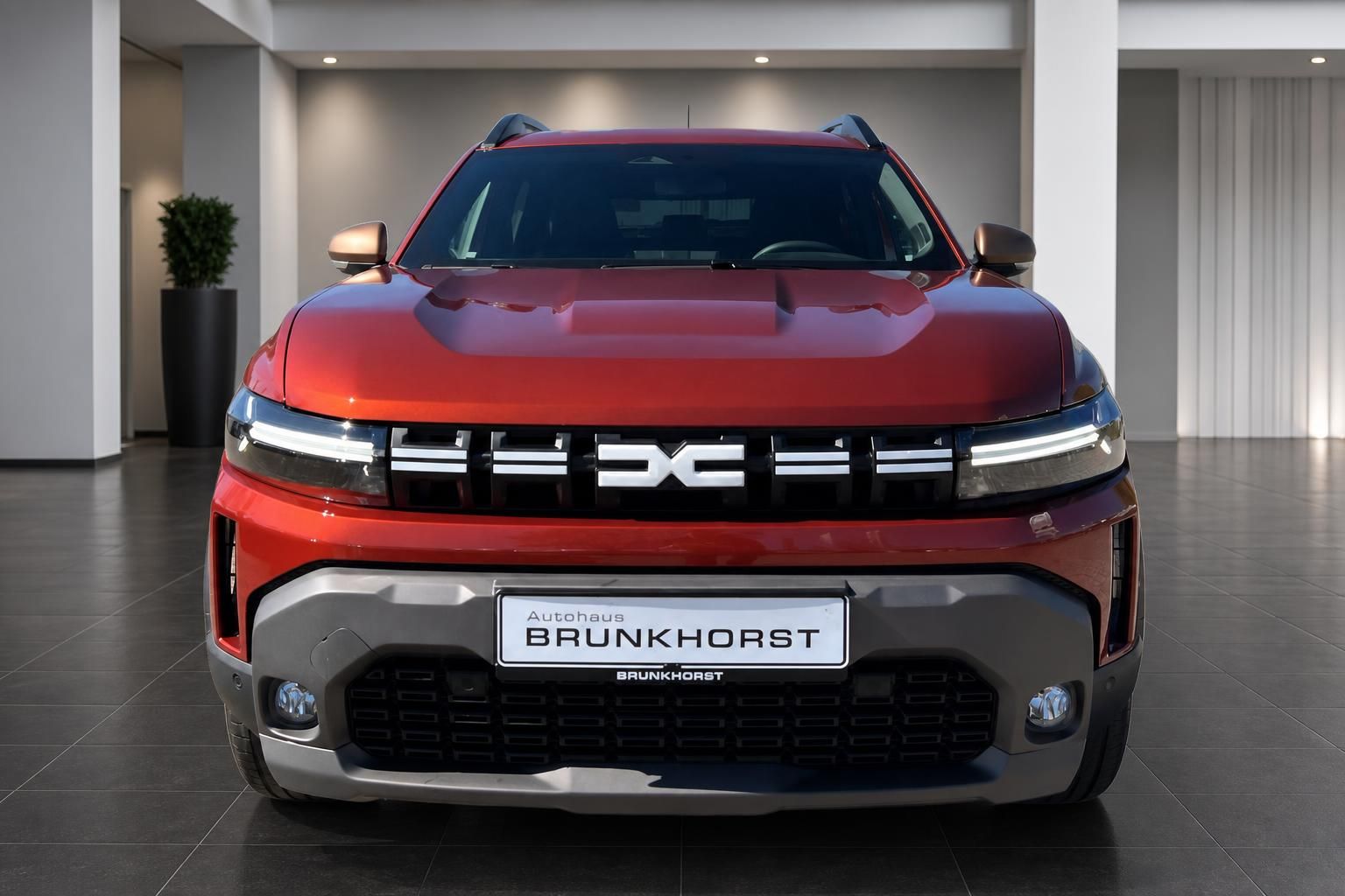 Dacia SUV Frontansicht in rot mit LED-Scheinwerfern und charakteristischem Kühlergrill im Autohaus