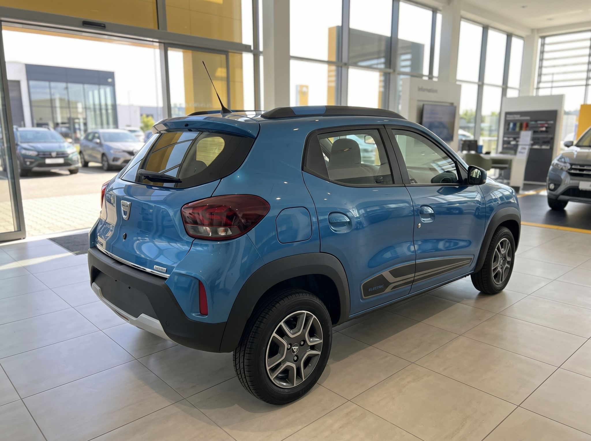 Dacia Spring blau - Heckansicht mit Rückleuchten im Autohaus-Showroom
