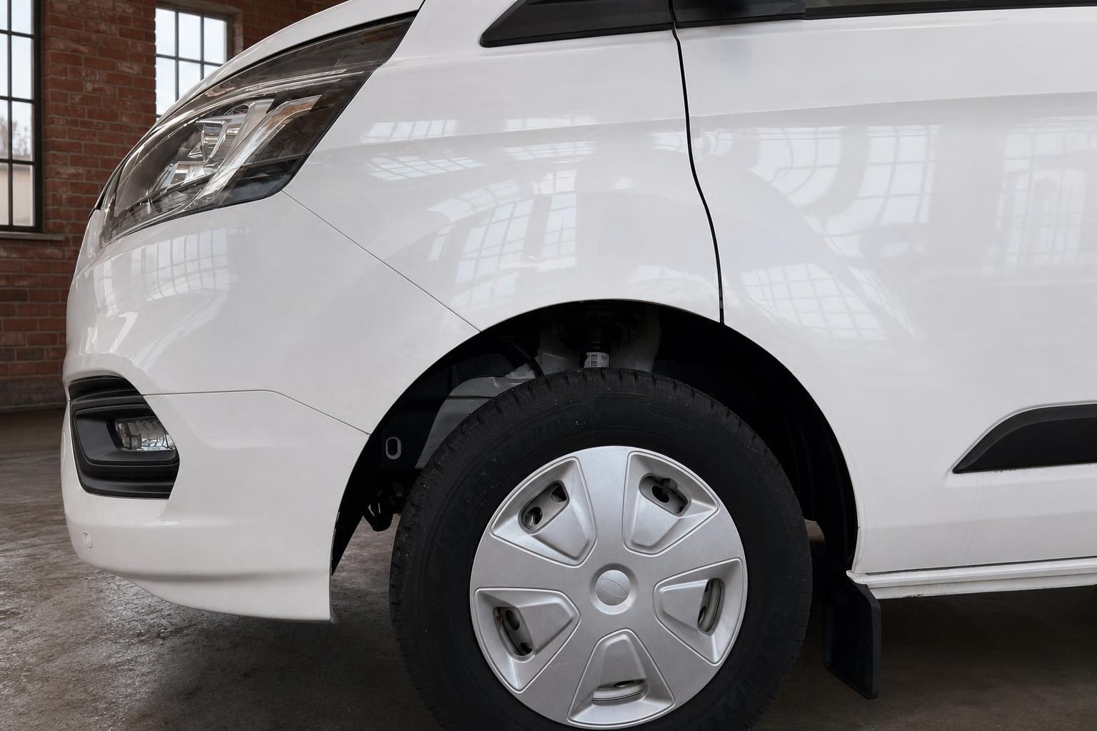 Ford Transit Custom weiss Detailansicht Vorderrad mit Radkappe und Stossfaenger