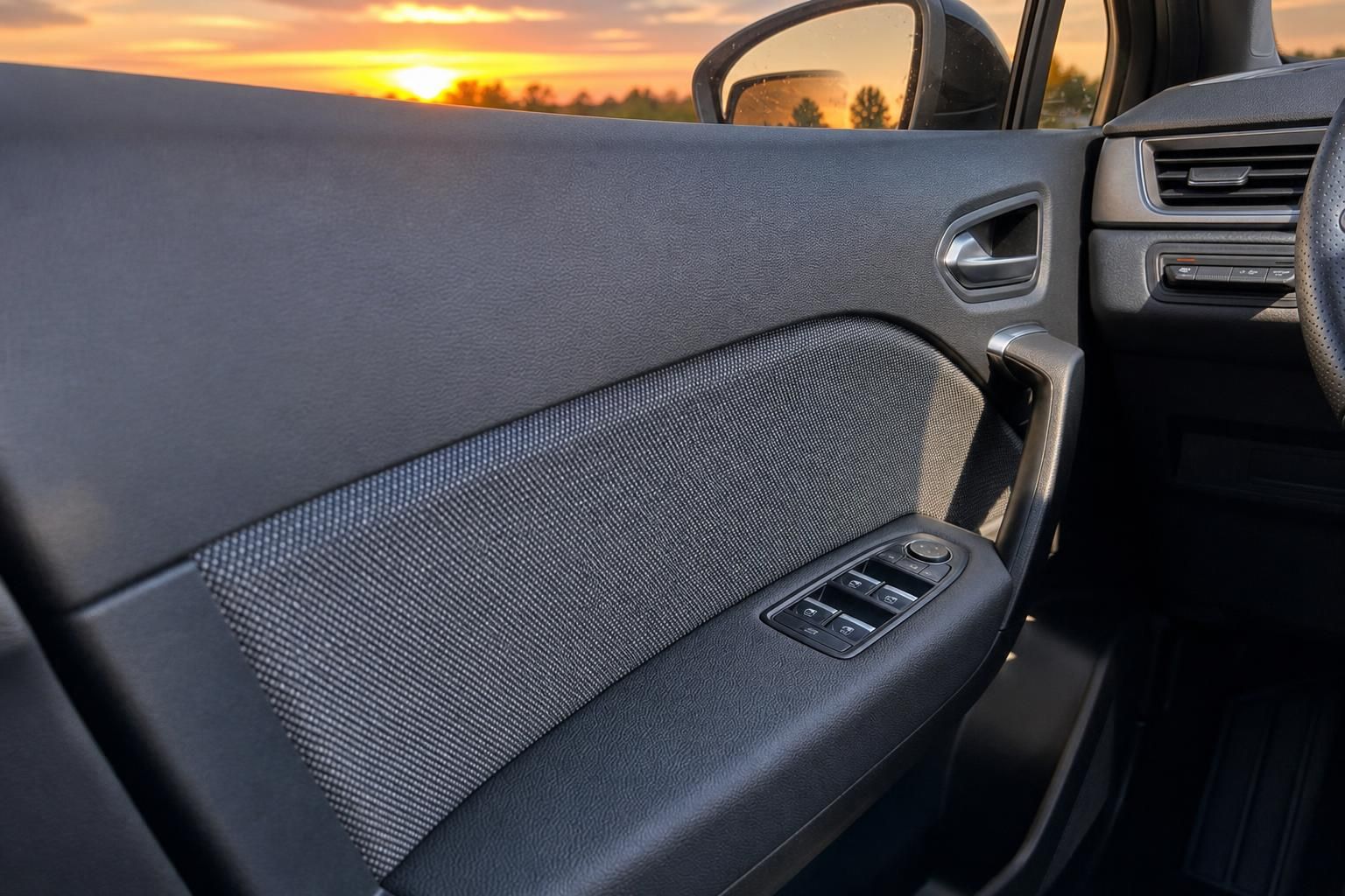Renault Fahrzeugtür von innen mit Fensterheberschaltern und Sonnenuntergang im Hintergrund