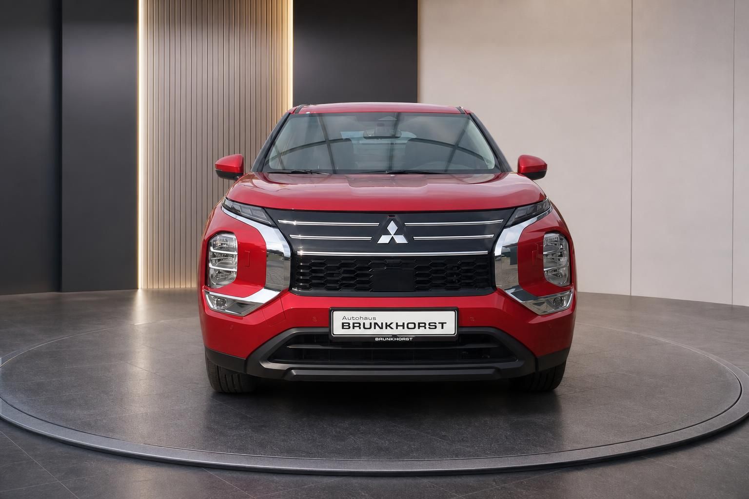 Roter Mitsubishi Outlander Frontansicht mit Autohaus Brunkhorst Kennzeichen im Showroom