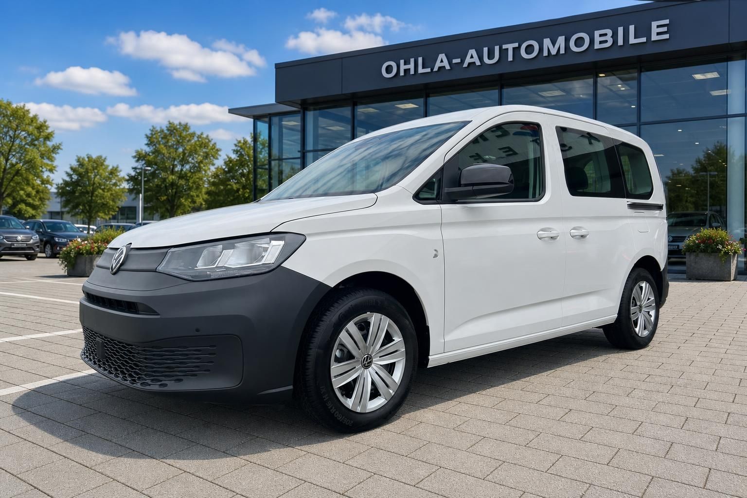 VW Caddy weiß Seitenansicht vor Autohaus Ohla-Automobile