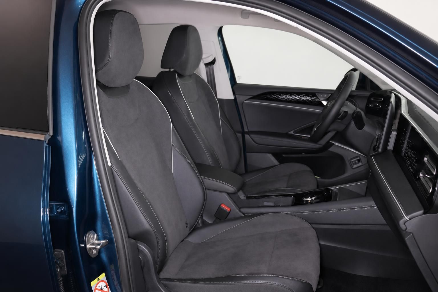 Blick durch geoeffnete Tuer auf Vordersitze und Cockpit eines blauen VW