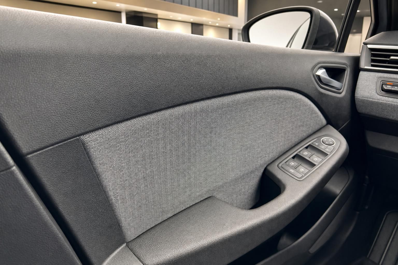 Fahrzeugtür innen mit grauer Stoffverkleidung und elektrischen Fensterhebern