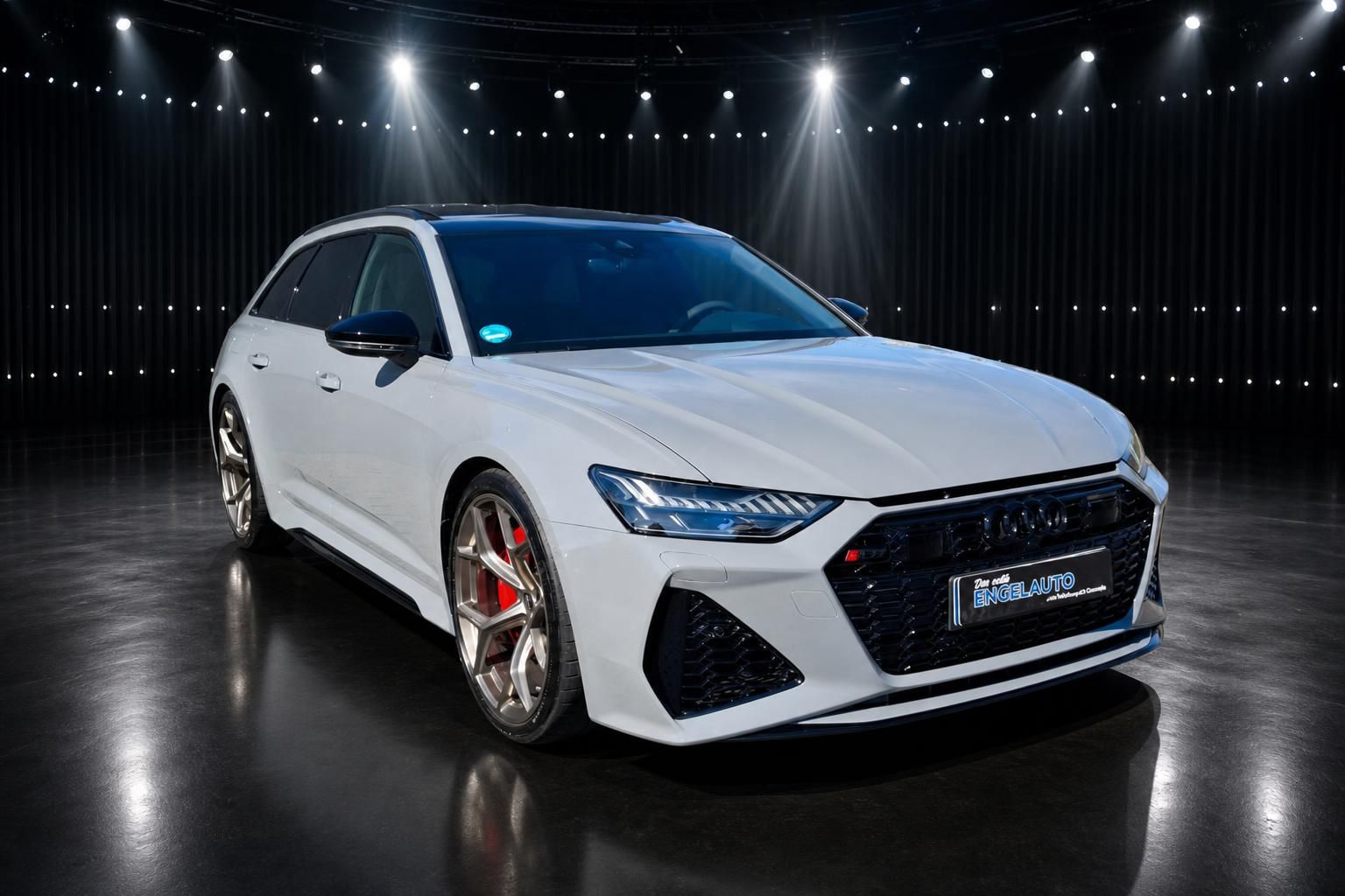 Audi RS6 Avant weiß Frontansicht schräg rechts im Fotostudio mit schwarzem Dach und roten Bremsen