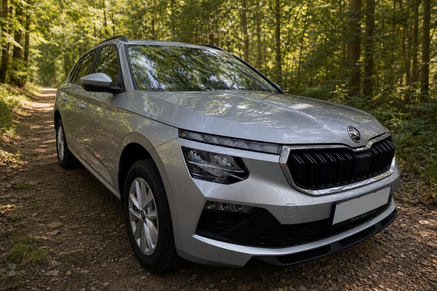 Skoda Kamiq SUV schräg von vorne in silber mit modernem Design und Alufelgen im Wald
