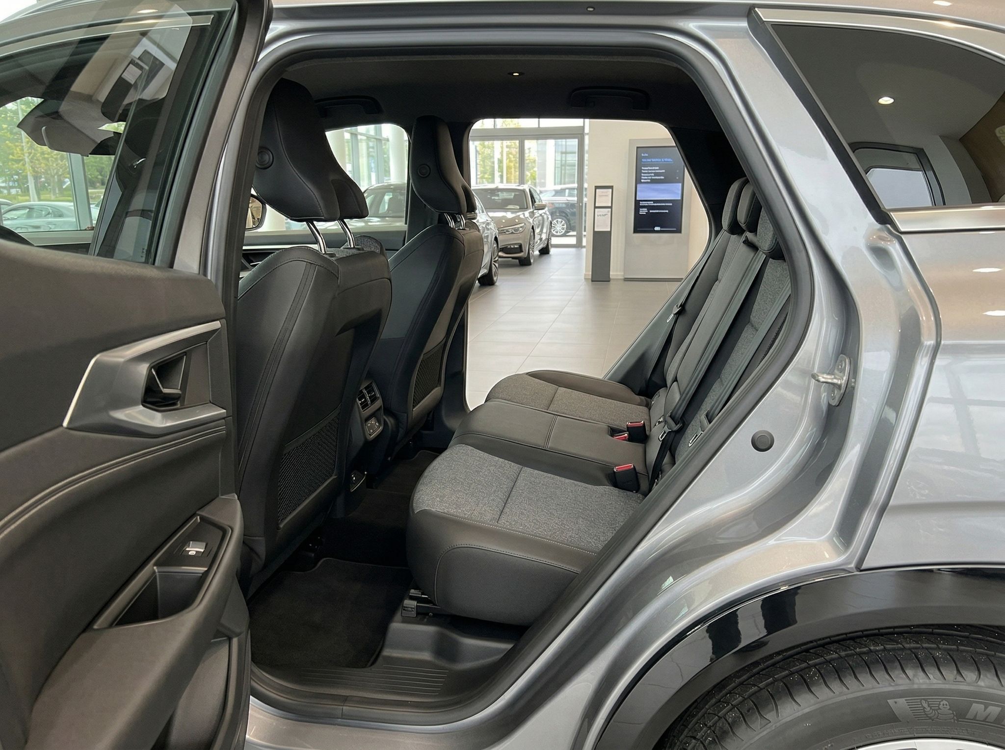 Fahrzeug Rücksitzbank mit grauen Stoffsitzen und offenen Türen im Autohaus Showroom