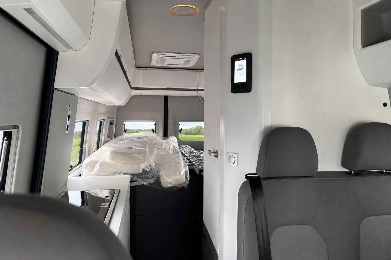 Wohnmobil Innenraum mit Bett, Küchenzeile und modernem Design in weißer Ausstattung