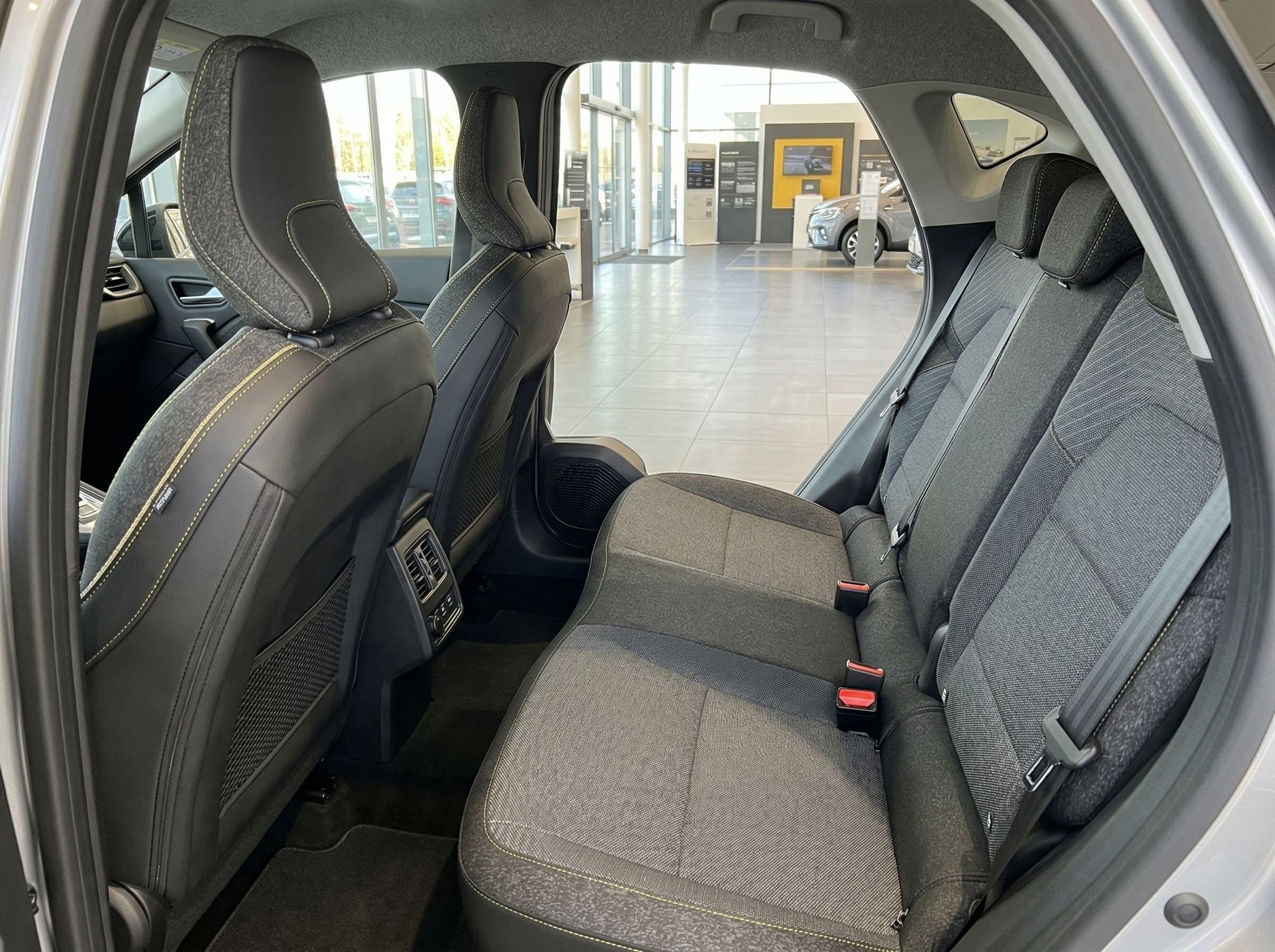 Renault Rücksitzbank mit grauer Polsterung und Blick durch offene Autotür in Autohaus-Showroom